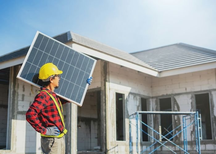Technician carrying a solar panel on site