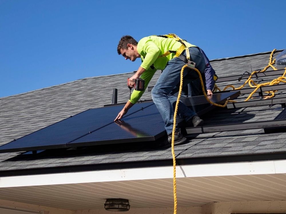 Technician installing solar panels on a roof